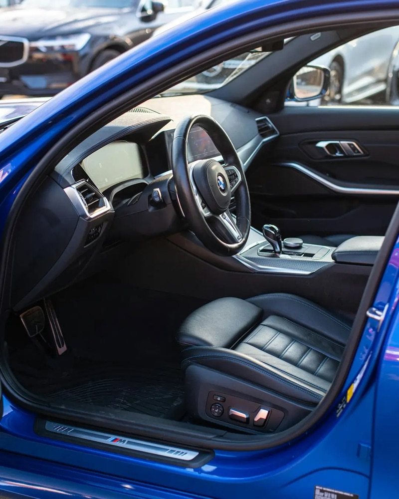 Blue BMW 3 Series with open door showing detailed black leather interior