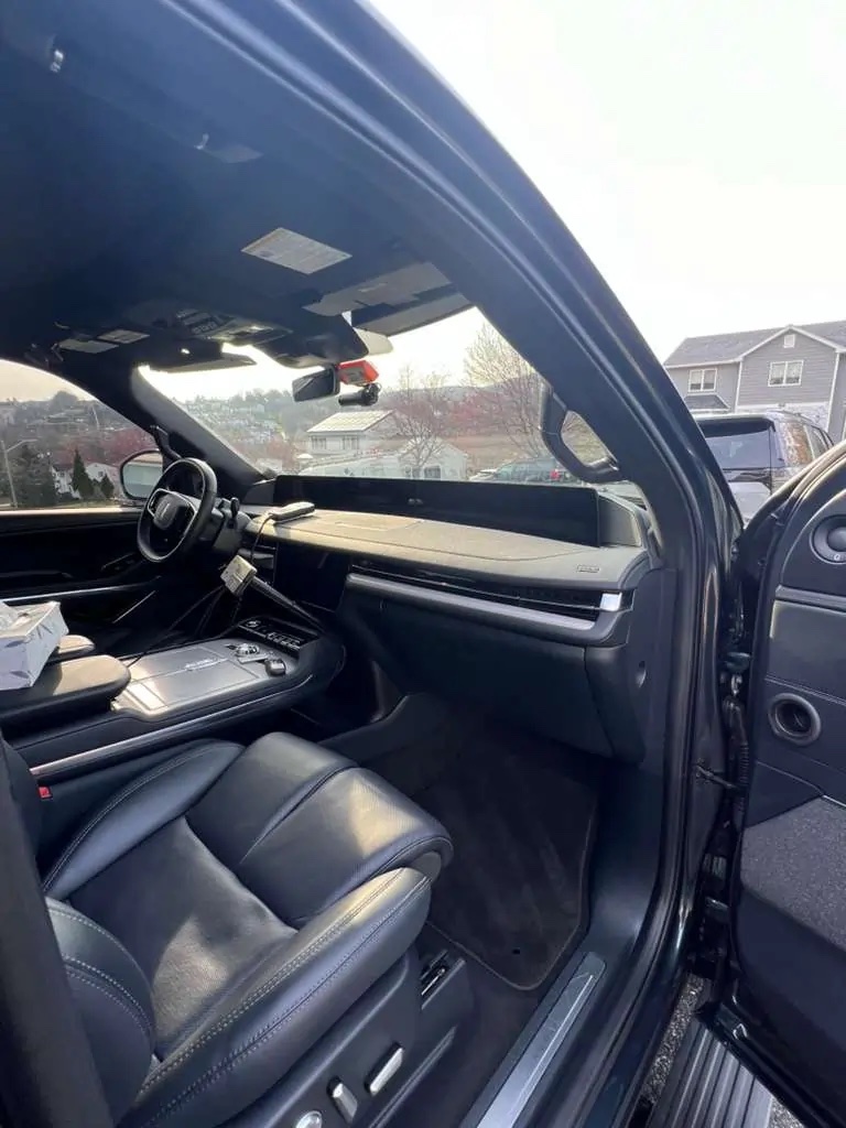 Dark full-size SUV with detailed black leather interior, photographed in a driveway