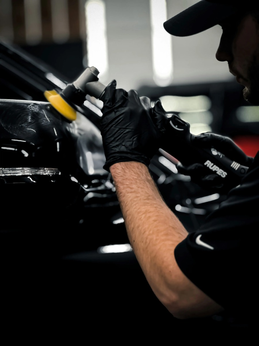 Gloved hand machine polishing a dark panel